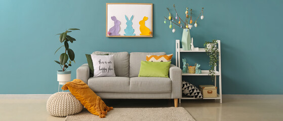 Interior of living room with Easter decor and grey sofa near blur wall