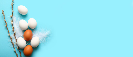 Pussy willow branches and eggs on light blue background with space for text