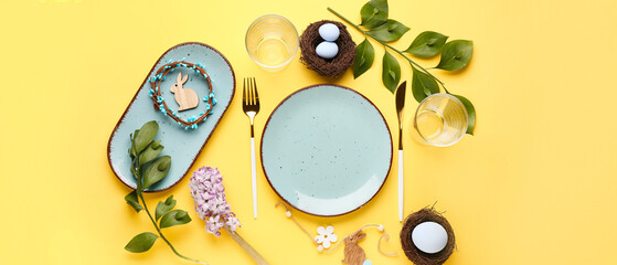 Stylish table setting for Easter dinner on yellow background