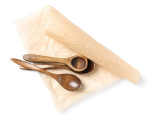 Wooden spoons and sheet of baking paper on white background