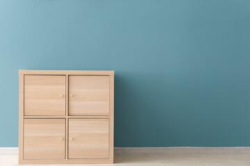 Wooden chest of drawers near blue wall