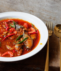 Canned sardines cooked with onions, garlic, cayenne pepper and green onions. Served on a white plate. more delicious eaten with warm rice. A close-up.