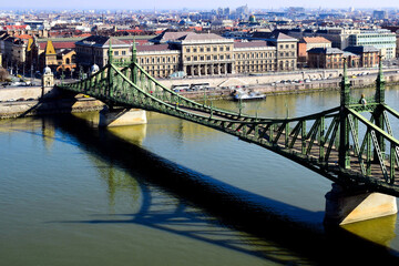 the Liberty bridge in Budapest over the Danube river. green steel suspension bridge. famous landmark and tourist attraction. The Great Market Hall in the background. travel and tourism in Europe