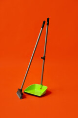 Plastic dustpan with cleaning broom on color background