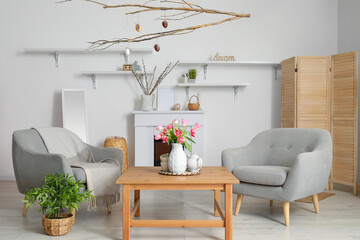 Interior of living room decorated for Easter celebration with armchairs and tree branches