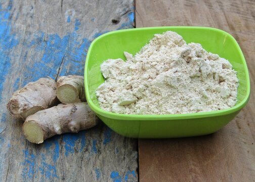 Ginger powder in a bowl on old wooden background 