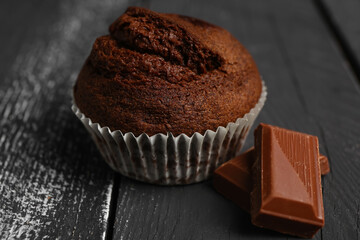 Tasty chocolate muffin on dark wooden background, closeup
