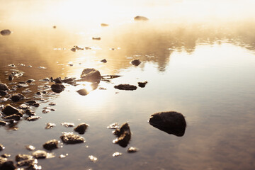 Soft smooth haze in golden sunbeams on water surface of calm river with ray, blinks, glares,...