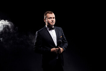 Man in costume holding microphone, posing on dark background, actor, singer, show, host of event