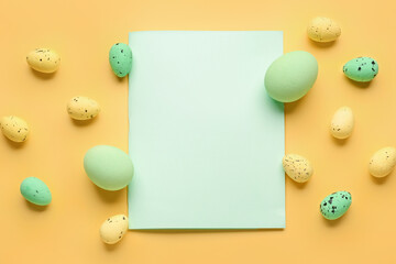 Composition with blank card and painted Easter eggs on yellow background