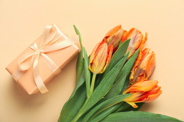 Gift box and beautiful tulip flowers on orange background. Hello spring