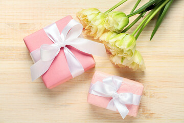 Gift boxes and beautiful tulip flowers on light wooden background. Hello spring