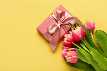 Gift box and beautiful tulip flowers on yellow background. Hello spring