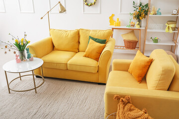 Interior of living room with yellow sofa, flowers and Easter eggs