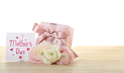 Greeting card with text MOTHER'S DAY, flowers and gift on table against white background