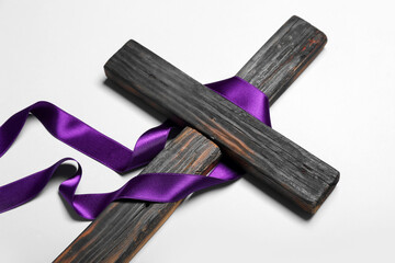 Wooden cross with purple ribbon on light background. Good Friday concept