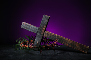 Crown of thorns, cross and palm leaf on table against dark purple background. Good Friday concept