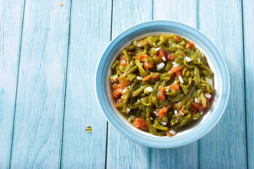 Salad of roasted red and green peppers with tomatoes and onions on a wooden background.