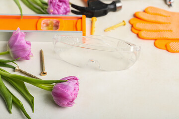 Builder's tools with tulips on white background, closeup. Hello spring