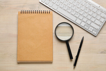 Blank notebook, pen, magnifier and keyboard on wooden background. World Poetry Day celebration