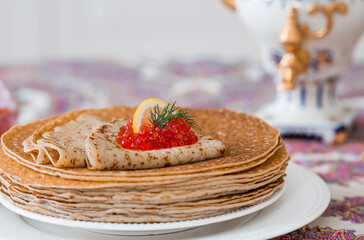 Russian traditions. Russian holiday Maslenitsa. Still life with a stack of pancakes, red caviar, lemon and a sprig of dill.