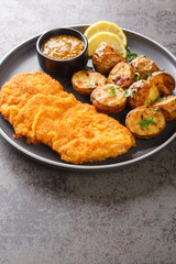 Munchner Schnitzel veal cutlets are brushed with a combination of sweet mustard and horseradish before coated in flour, eggs and breadcrumbs then fried closeup on the plate on the table. Vertical
