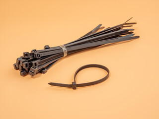 Black plastic cable ties on an orange background. Close-up.