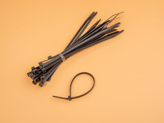 Black plastic cable ties on an orange background. Close-up.