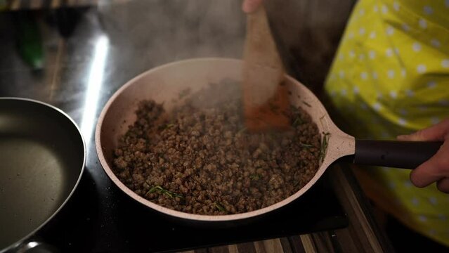 Cook mixes minced meat with spices in a pan with a spatula