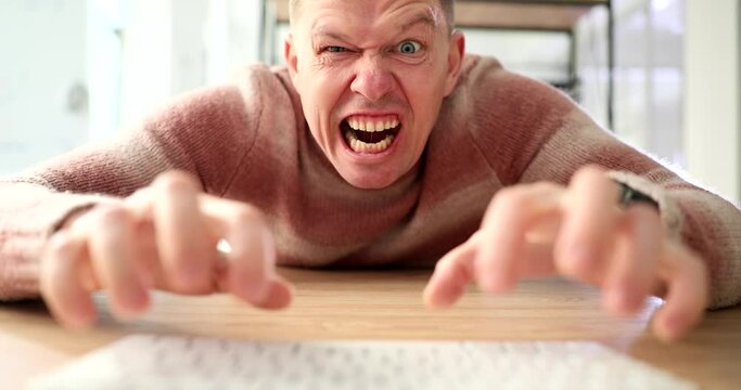 Portrait of angry businessman freelancer shaking computer monitor