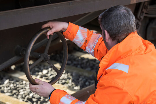 Ein Bahnmitarbeiter zieht eine Feststellbremse an einem Waggon an 