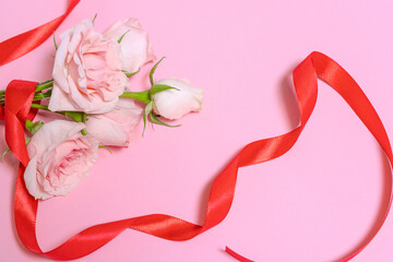 Beautiful pink roses and red ribbon on a light pink background, space for text. Celebrating Valentine's Day and Mother's Day with Women's Day