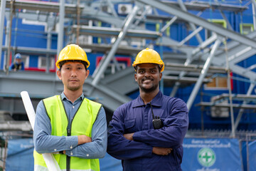 Portrait of African American Technician, Asian Engineer standing arms crossed together. Group of Multi-Ethnic Blue-collar worker. Teamwork of Architect review plans at construction site.