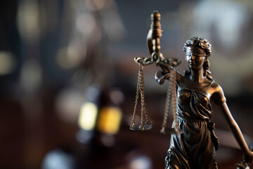 Law and justice concept. War crimes. Gavel and Themis sculpture in lawyers office. Gray bokeh background.