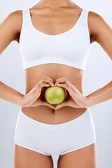 Nutrition, apple and woman hands on stomach in heart shape for digestion, detox diet and studio...