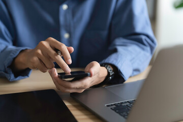 Casual businessman and freelancer online working on a laptop computer and using mobile phone cloud...