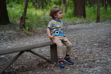 Little boy in summer city Park sitting on a bench. Selective focus
