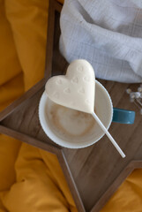 A cup of cappuccino and a chocolate heart. View from above