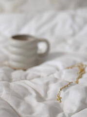 Fototapeta na wymiar A cup of coffee in bed and beads for Christian prayer rosaries