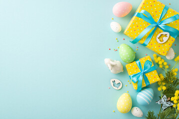 Easter concept. Top view photo of vivid yellow gift boxes with blue bows colorful easter eggs ceramic bunny mimosa flowers and sprinkles on isolated pastel blue background with blank space