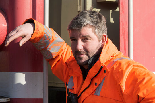 Portrait eines Arbeiters in orangfarbener Arbeitskleidung