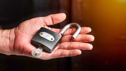 Master key and unlocked padlock in hand. 