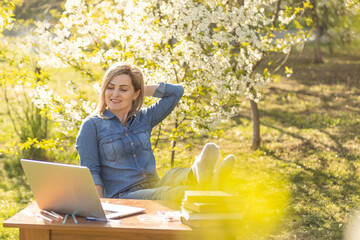 Girl with a laptop on the spring meadow.