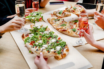Hands taking pizza slices from wooden table