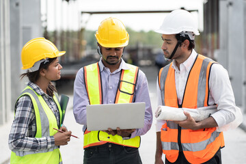 India engineer man holding laptop computer with team engineer at precast site work	