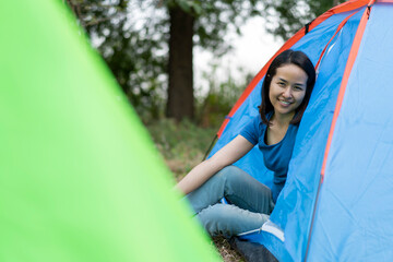 Young Asian woman Smiley Relaxing with tent in nature at sunset.