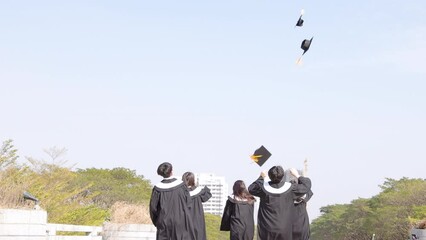 Happy students running and throwing graduation hats in air