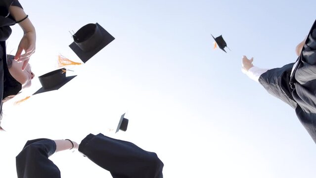 Happy students throwing graduation hats in air