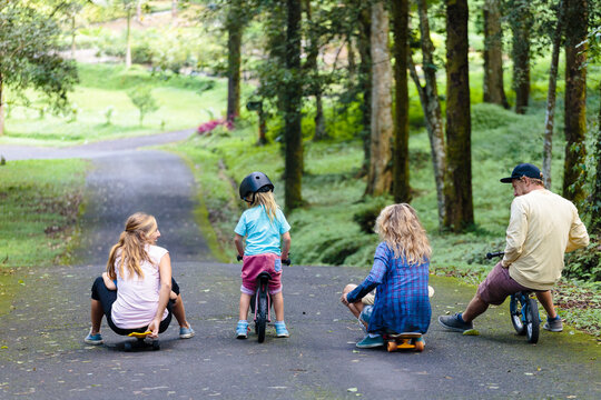 Family with skateboards and bicycles playing in park, Bedugul, Bali, Indonesia