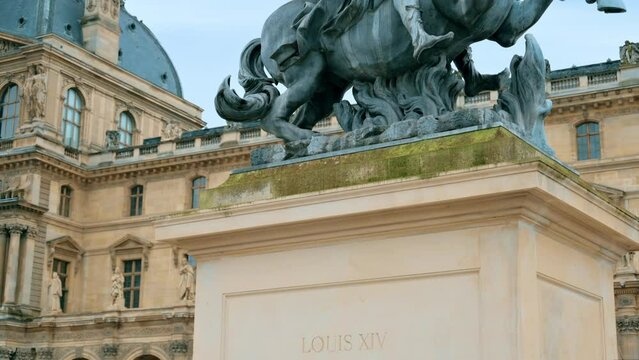 View of the Louis XIV Statue on the Napoleon Courtyard in Paris, France. Louvre Palace on the background, cloudy weather